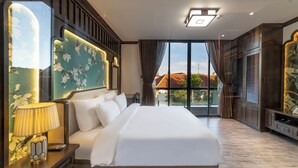 A spacious hotel room with a large bed, a nightstand, a lamp, and a TV. The room has a large window with curtains and a view of buildings outside. - Le House Dalat  (Cam Ly - Da Lat)