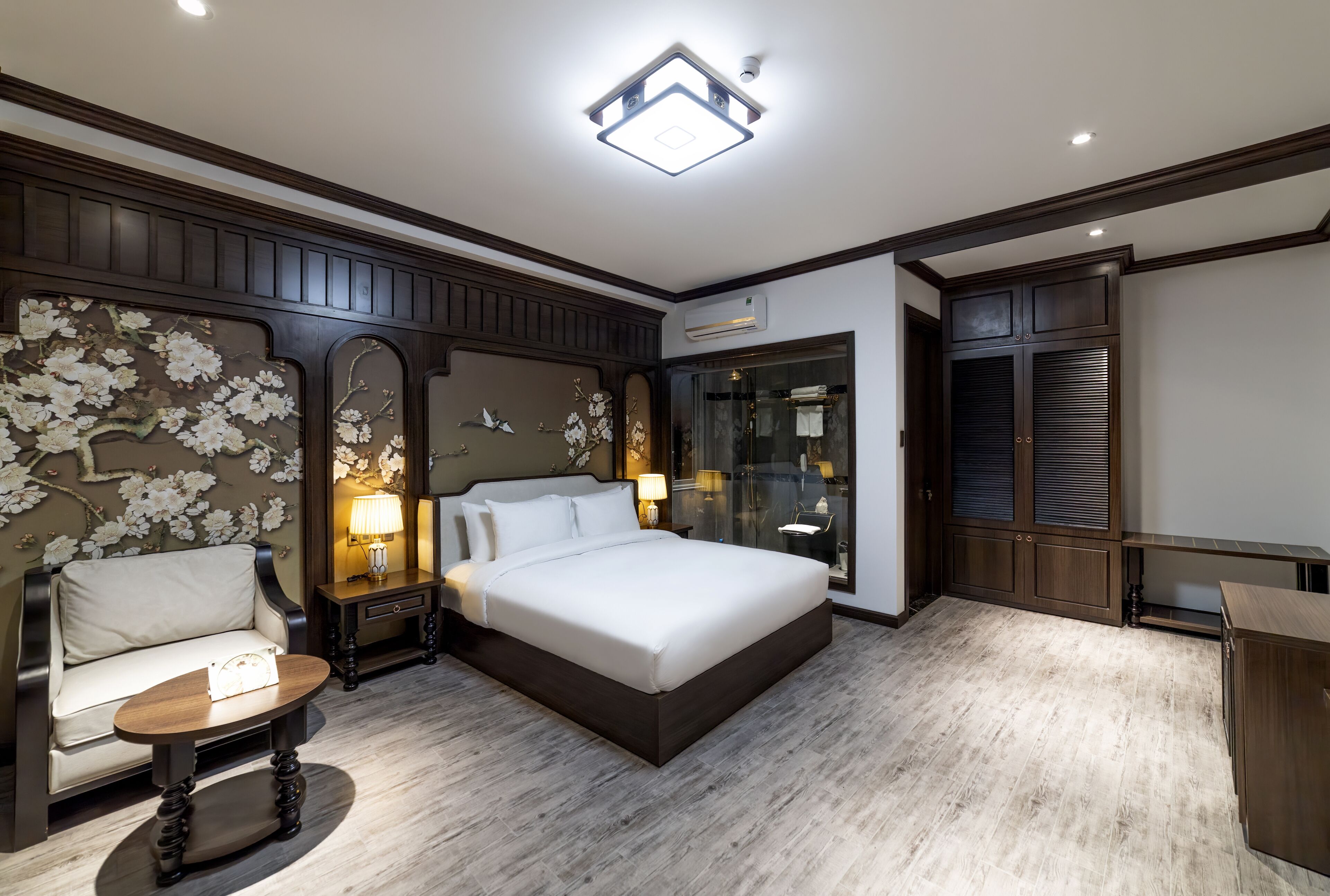 A bedroom with a large bed, a bedside table, a chair, and a wardrobe.