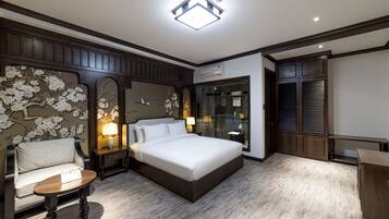 A bedroom with a large bed, a bedside table, a chair, and a wardrobe.