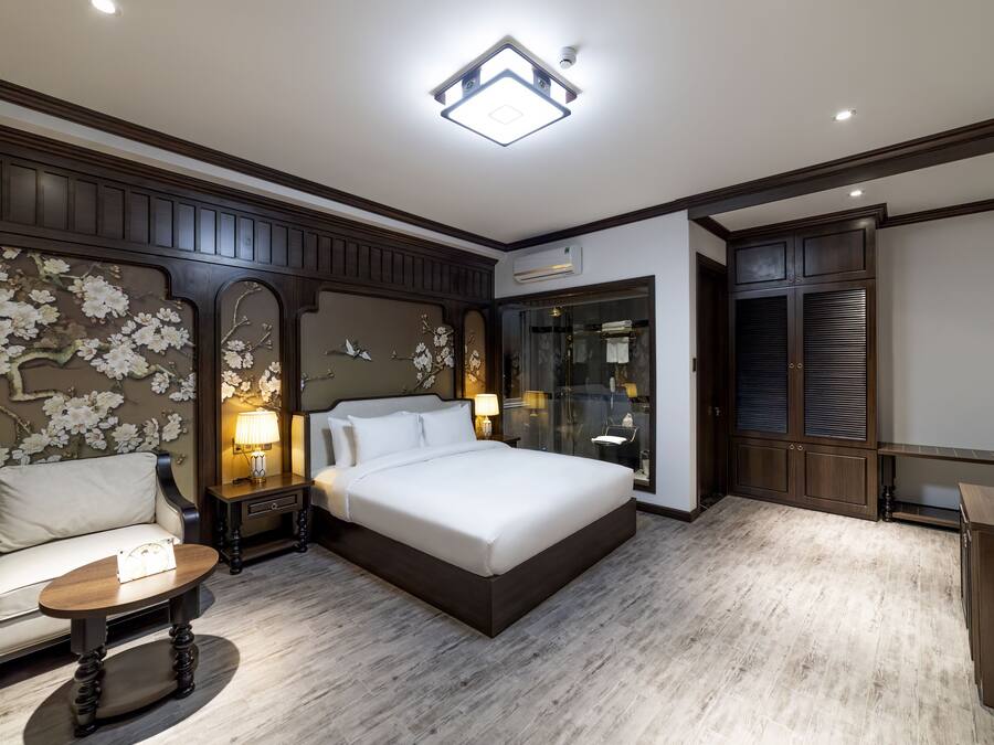 A bedroom with a large bed, a bedside table, a chair, and a wardrobe.