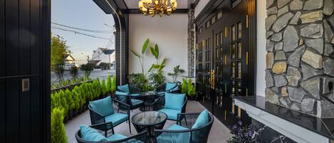 An outdoor patio with wicker furniture and potted plants.