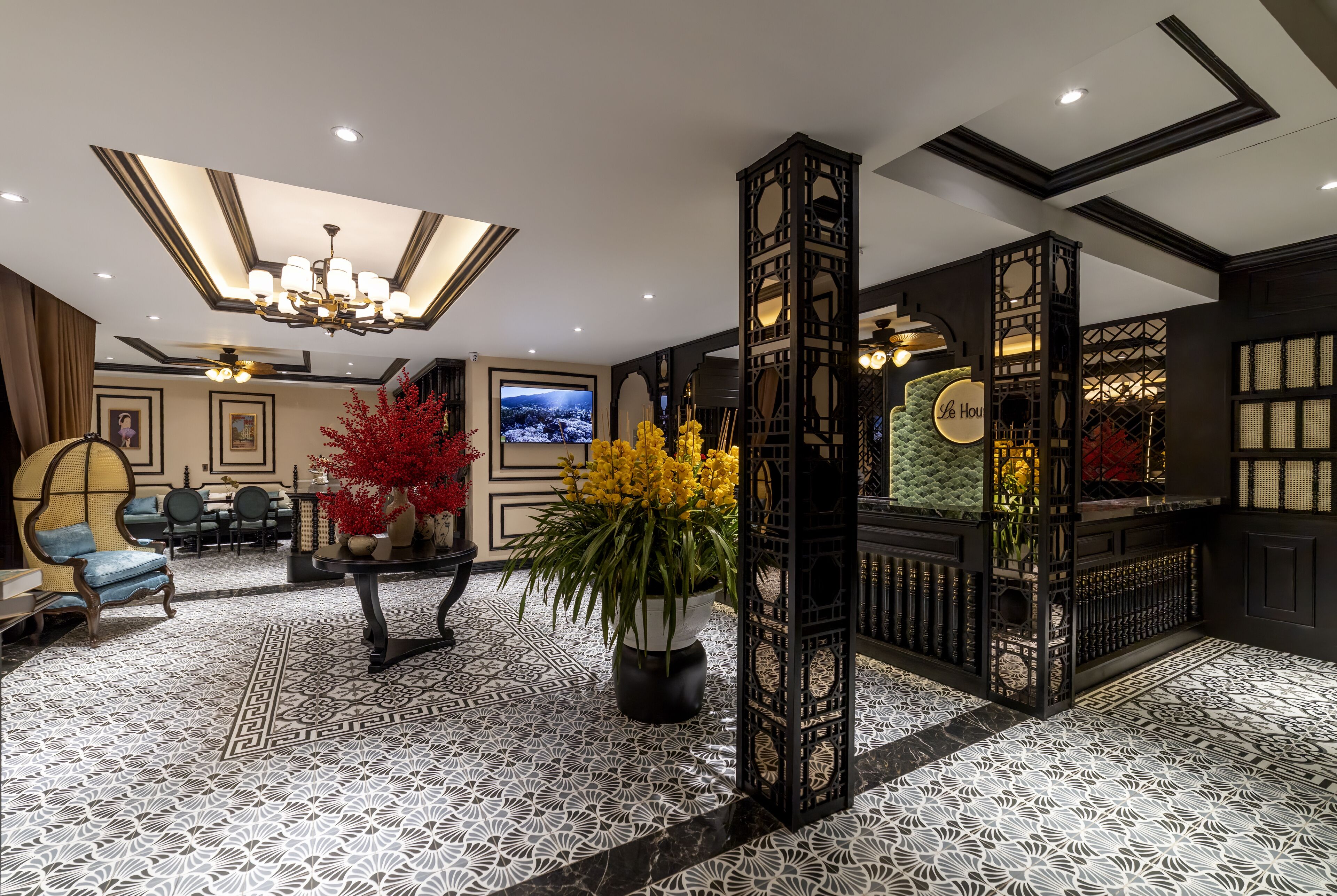 Un'accogliente hall d'albergo con pavimento decorato, un lampadario, un televisore e la reception.