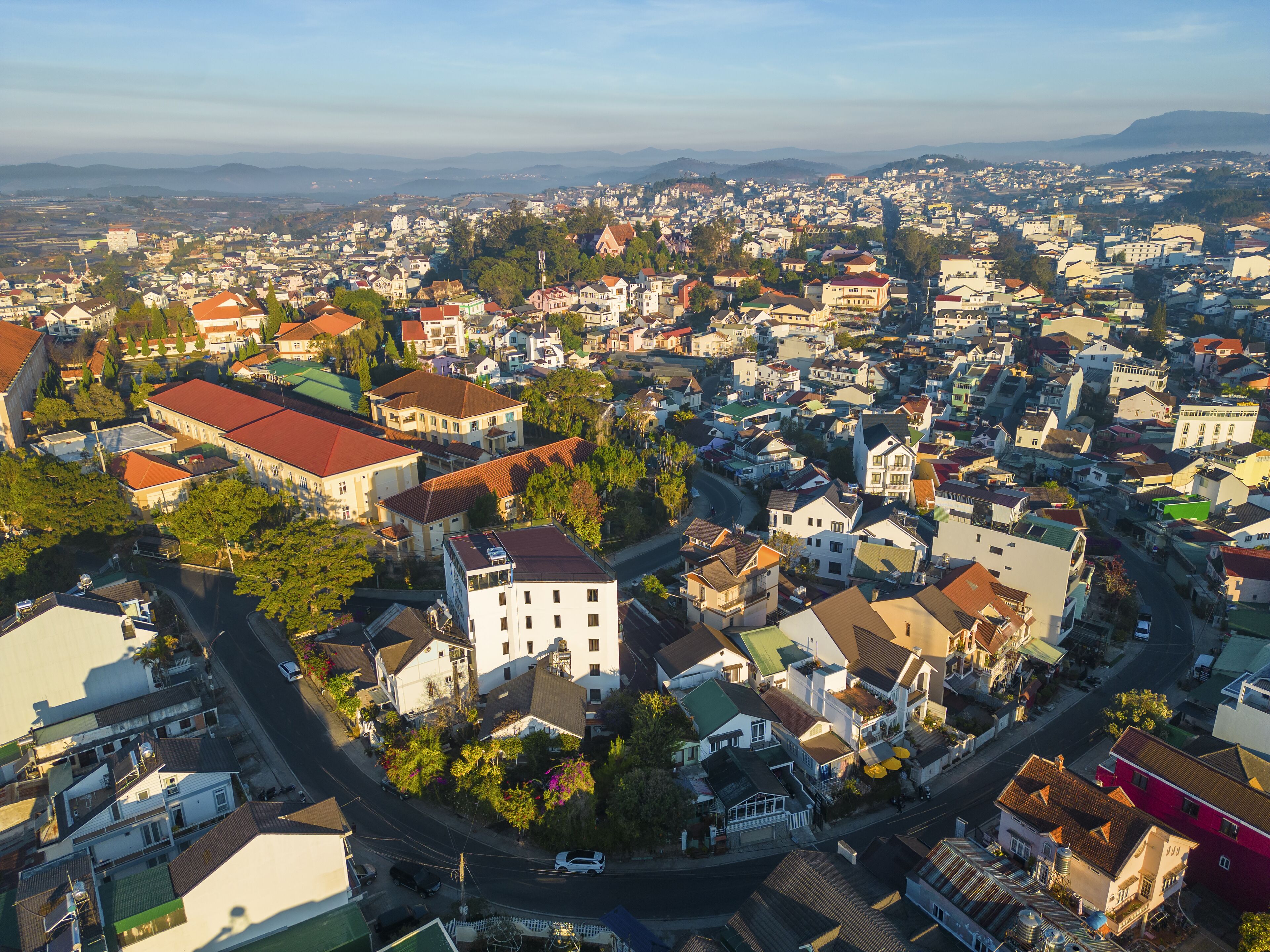 An aerial view of a densely populated urban area with a mix of residential buildings, roads, and greenery.