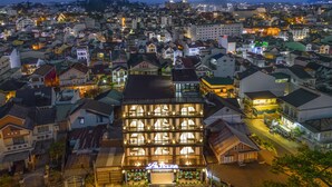 A multi-story hotel with a ground-level restaurant, surrounded by a densely packed urban area with various buildings and streetlights. - Le House Dalat  (Cam Ly - Da Lat)