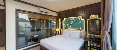 A modern hotel room with a large bed, a glass shower enclosure, a vanity with a mirror, and a decorative headboard.