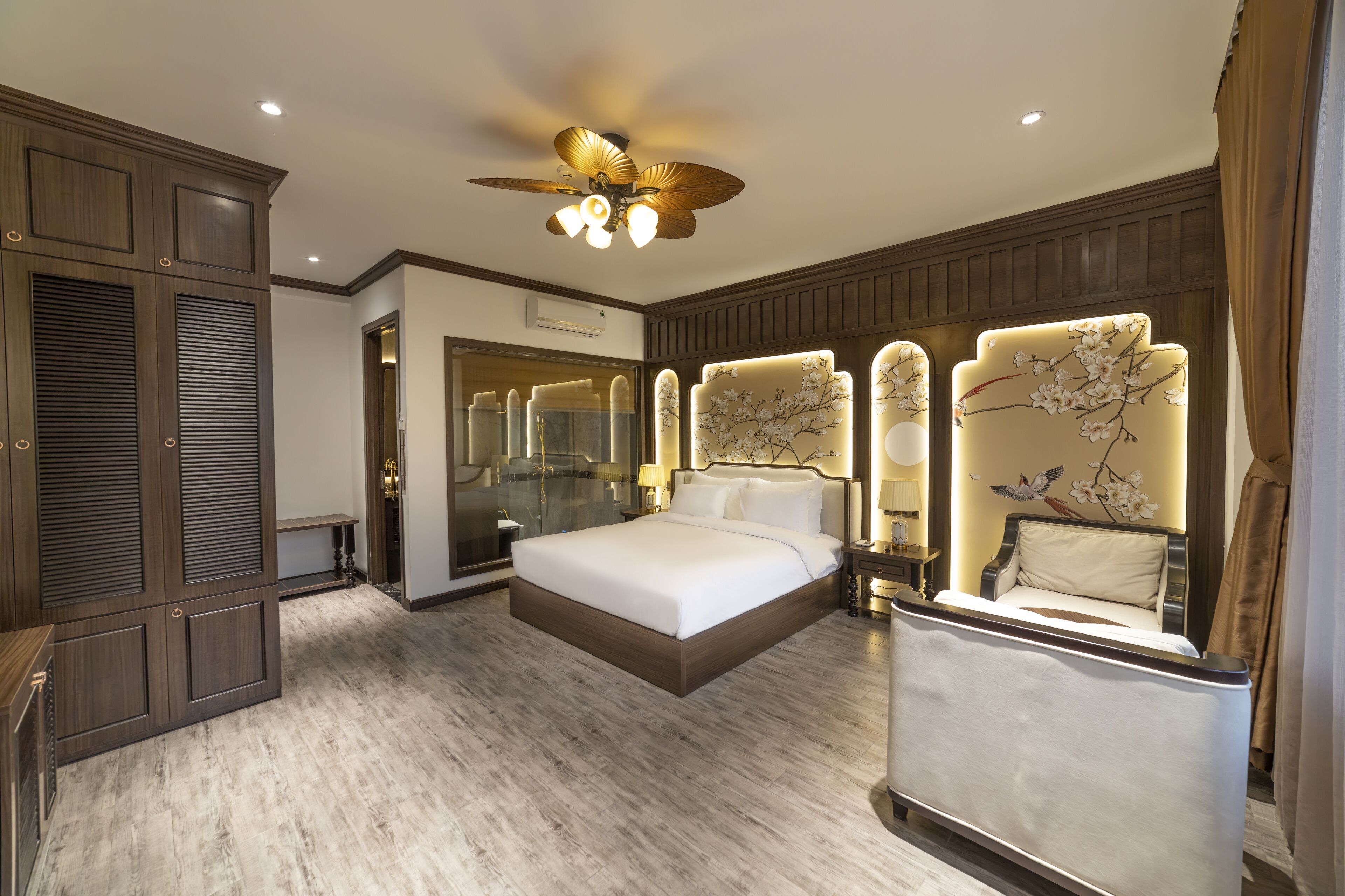 A spacious bedroom with a large bed, a ceiling fan, and a mirror with a floral design.