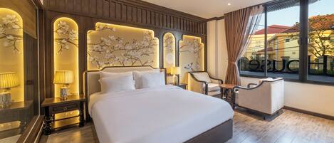 A hotel room with a large bed, a nightstand with a lamp, a chair, and a view of the outside.