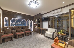 Egy modern nappali, amelyben egy kanapé-garnitúra, egy fehér karosszék és egy üveg válaszfal található, melyen át kilátás nyílik.