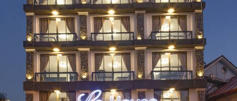 Un hotel de varios pisos con un llamativo letrero iluminado que dice "Le House".