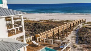 A beachfront property with a wooden deck, a swimming pool, and a view of the ocean. - Lavish Beach Sanctuary with Private Pool and Boardwalk | Sugar Shores by Kaiser Vacation Rentals (Gulf Shores)