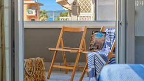 A balcony with a wooden chair, a striped towel, and a bag. - Bilocale Vista Mare Giorgio (Alghero)