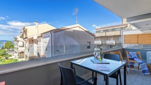 A balcony with a table, chairs, and a view of neighboring buildings. - Bilocale Vista Mare Giorgio (Alghero)