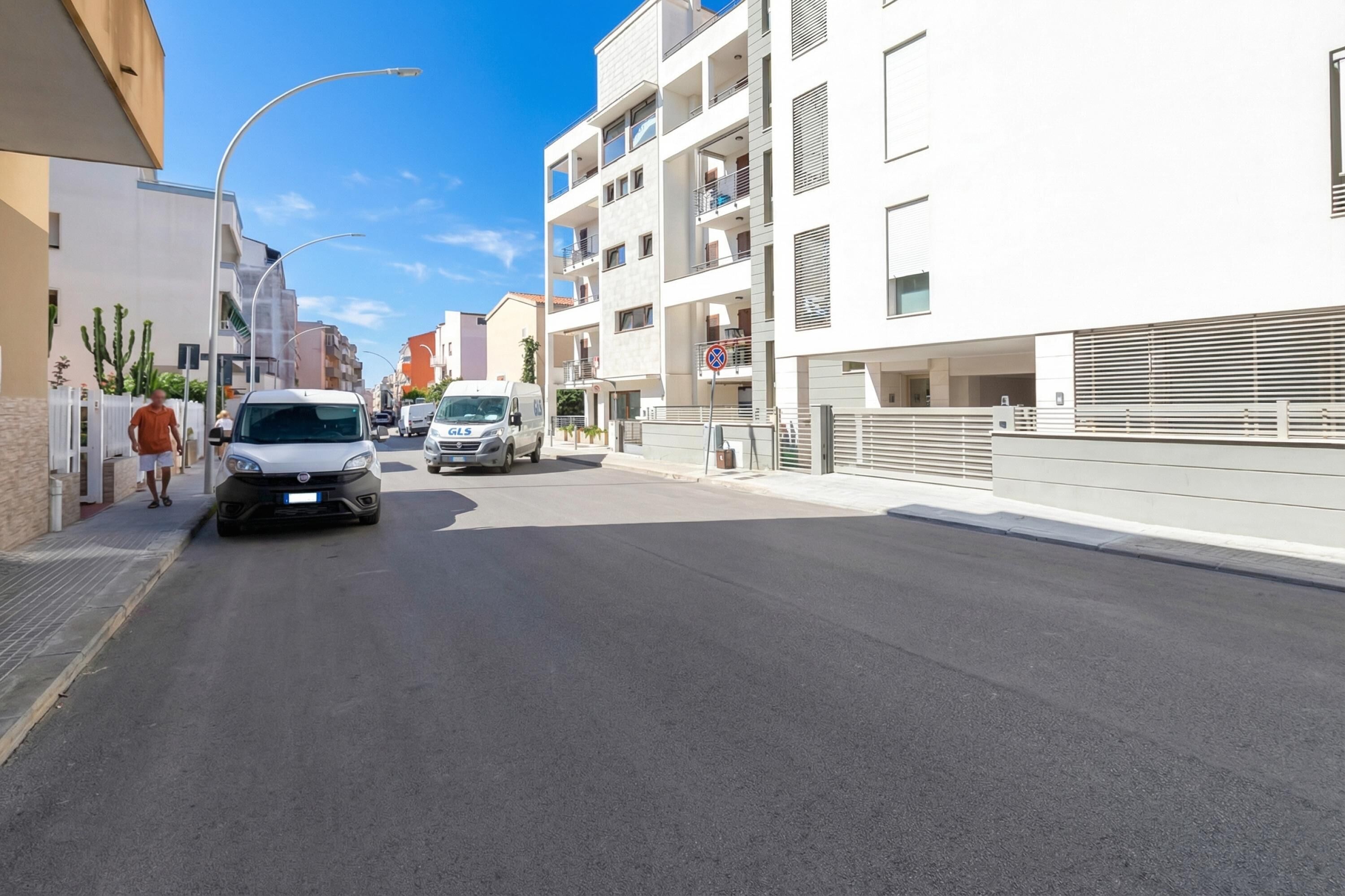 A street with modern buildings, a white van, and a pedestrian.