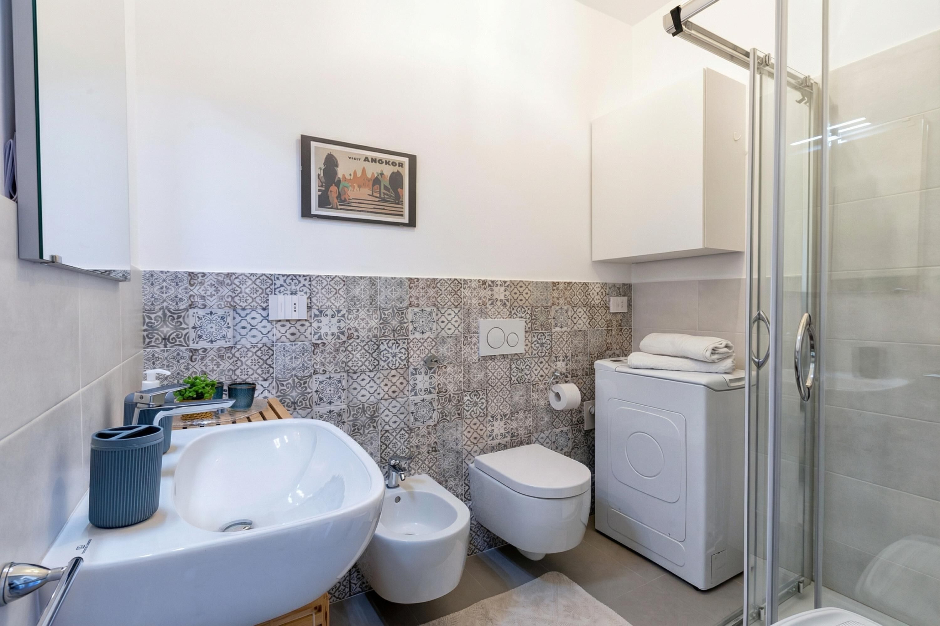 A bathroom with a large sink, bidet, toilet, and glass shower enclosure.
