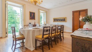 A dining room with a table set for six, wooden chairs with yellow cushions, a chandelier, and paintings on the walls. - Villa Cardinal Ciceri - Penthouse Apartments (San Fermo della Battaglia)