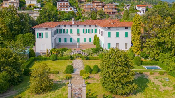 A large, white building with green shutters, surrounded by lush greenery and a well-maintained garden. - Villa Cardinal Ciceri - Penthouse Apartments (San Fermo della Battaglia)