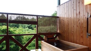 Área de banho em águas termais de madeira, com vista para vegetação exuberante.