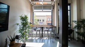 Un intérieur moderne avec un coin repas, de grandes fenêtres et des plantes en pot.