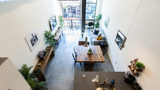 Une cuisine moderne dotée d’un îlot central, d’un coin repas avec une table en bois et offrant une vue sur la ville grâce à de grandes fenêtres.