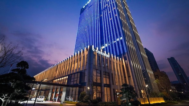 Un moderno hotel de altura con un diseño vertical distintivo, con ventanas iluminadas y una entrada destacada.