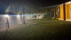 A nighttime view of a building with a brick wall and a grassy area.