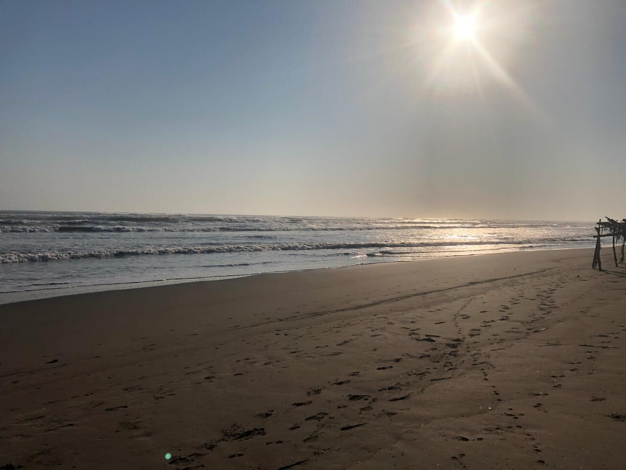 Una playa con huellas y una estructura de madera a la derecha.