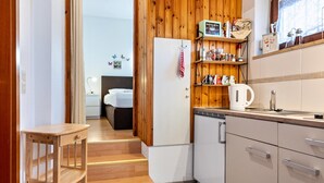 Una cucina compatta con elementi in legno, un frigorifero bianco e una macchina del caffè sul ripiano.