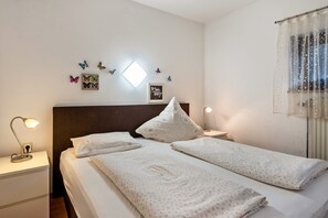 Un lit bien fait, avec une tête de lit, une lampe de chevet et un luminaire fixé au mur.