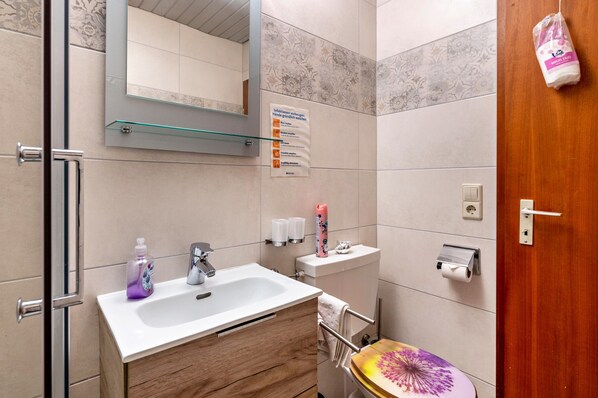 Un baño con lavamanos, espejo, inodoro y zona de ducha.