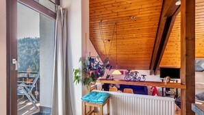Una habitación con techo de madera, vista a un balcón, un radiador, una silla y una mesa.