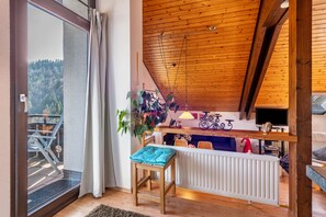 Une pièce avec un plafond en bois, une vue sur un balcon, un radiateur, une chaise et une table.