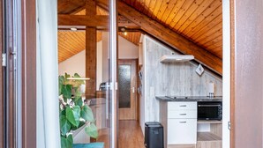 Una cocina moderna con vigas de madera, microondas y un cubo de basura.