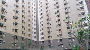 A high-rise residential building with multiple balconies, a flat facade, and some greenery in the foreground. - OYO Life 93251 Apartement Gateway Cicadas By Alugada (Bandung)