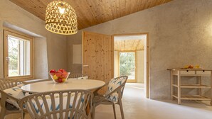 Un coin repas avec une table ronde, des chaises et un saladier rempli de fruits.