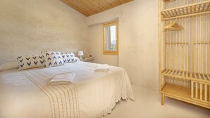Une chambre avec un plafond en bois, un lit avec une literie blanche, une fenêtre et une armoire en bois.