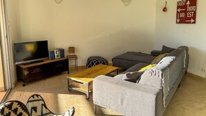 Een woonkamer met een bank, een televisie, een houten salontafel en een gestreept fauteuil.