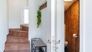 A staircase leading to a room with a wooden wall, a coat rack with greenery, and a toilet visible through an open door. - 'Feichtenhäusl 1' with Mountain View, Private Terrace and Wi-Fi (Westendorf)
