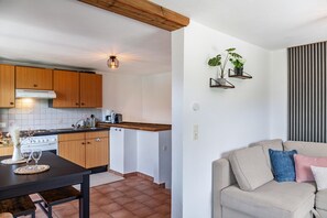 Une cuisine moderne avec des meubles en bois, un four encastré et un coin repas comprenant une table et des chaises.