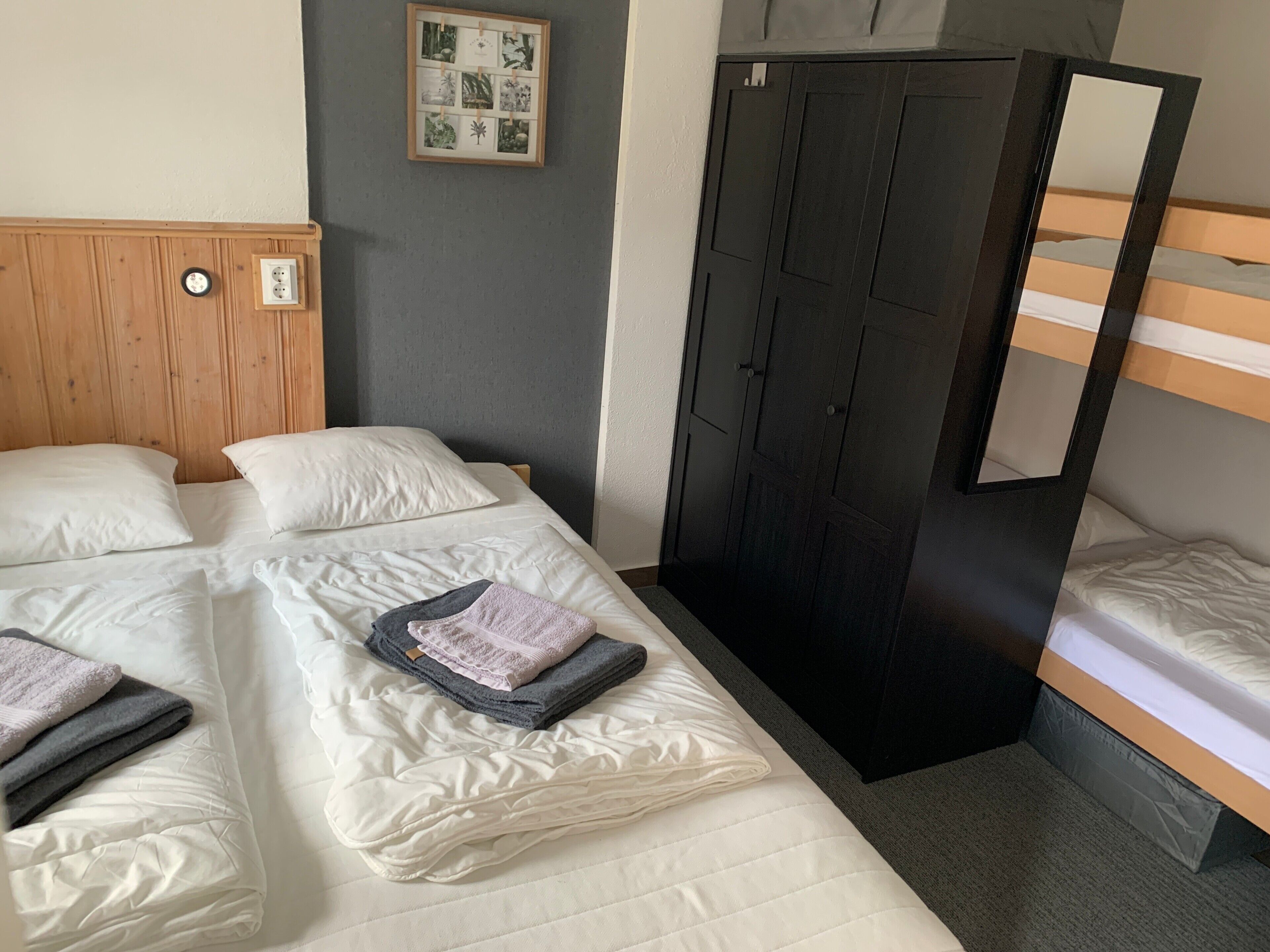 Ein Hotelzimmer mit Bett, Schrank, Spiegel und einem an der Wand hängenden Bild.