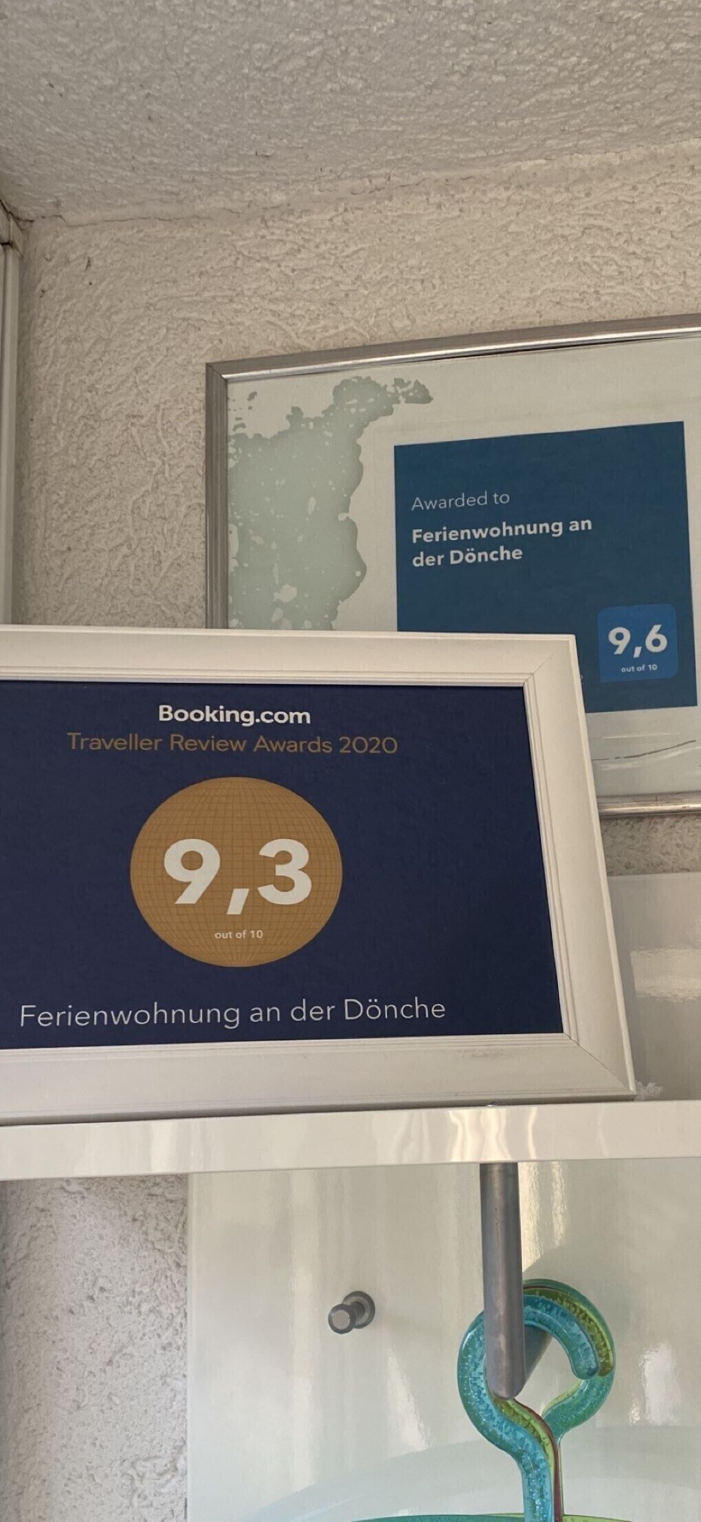 Framed awards for a hotel, including a 9.3 out of 10 rating from Booking.com and a 9.6 out of 10 from another source.