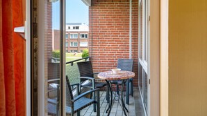 A balcony with a brick wall, a table with chairs, and a view of buildings in the background.