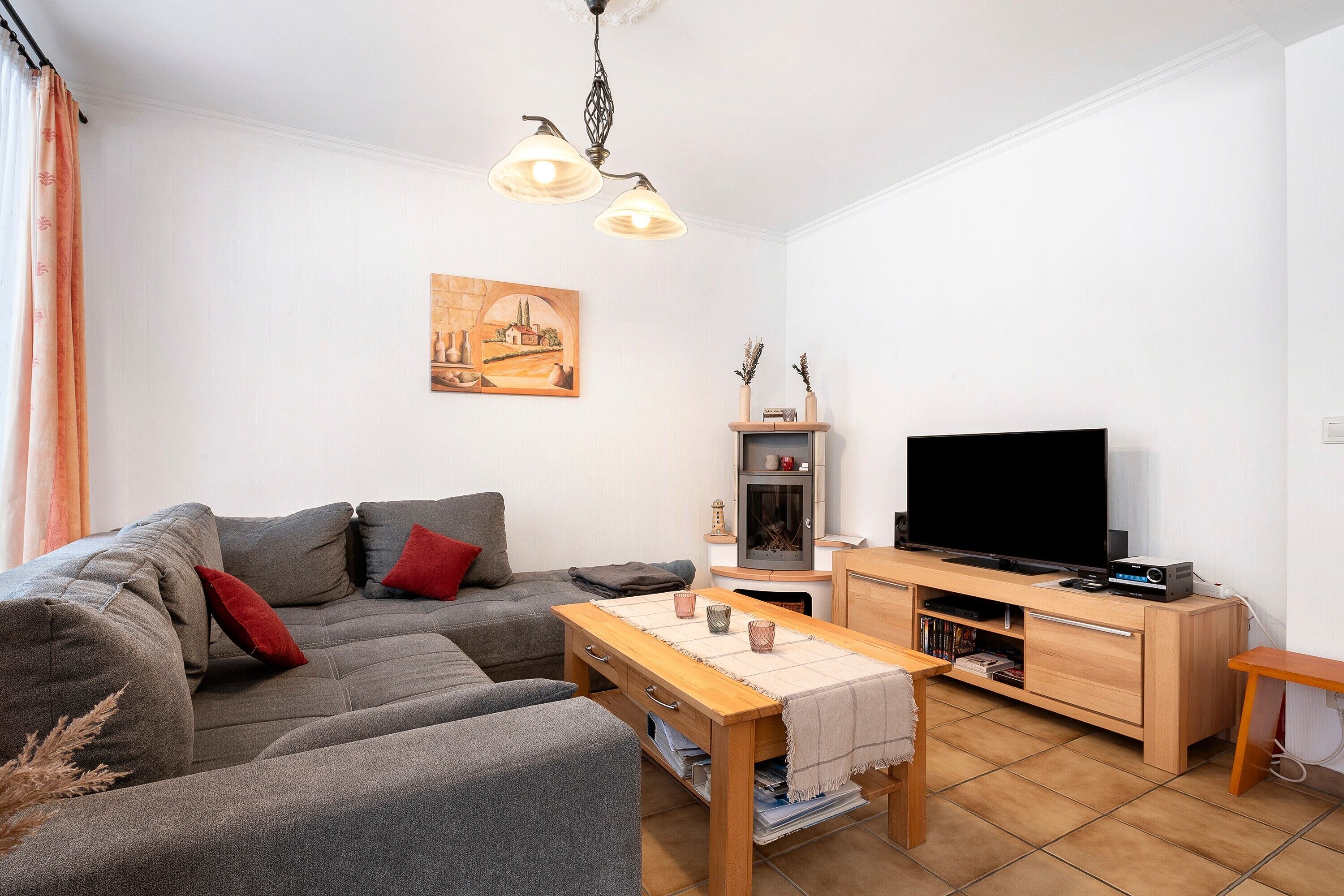 Een woonkamer met een bank, televisie, houten tafel en een open haard.