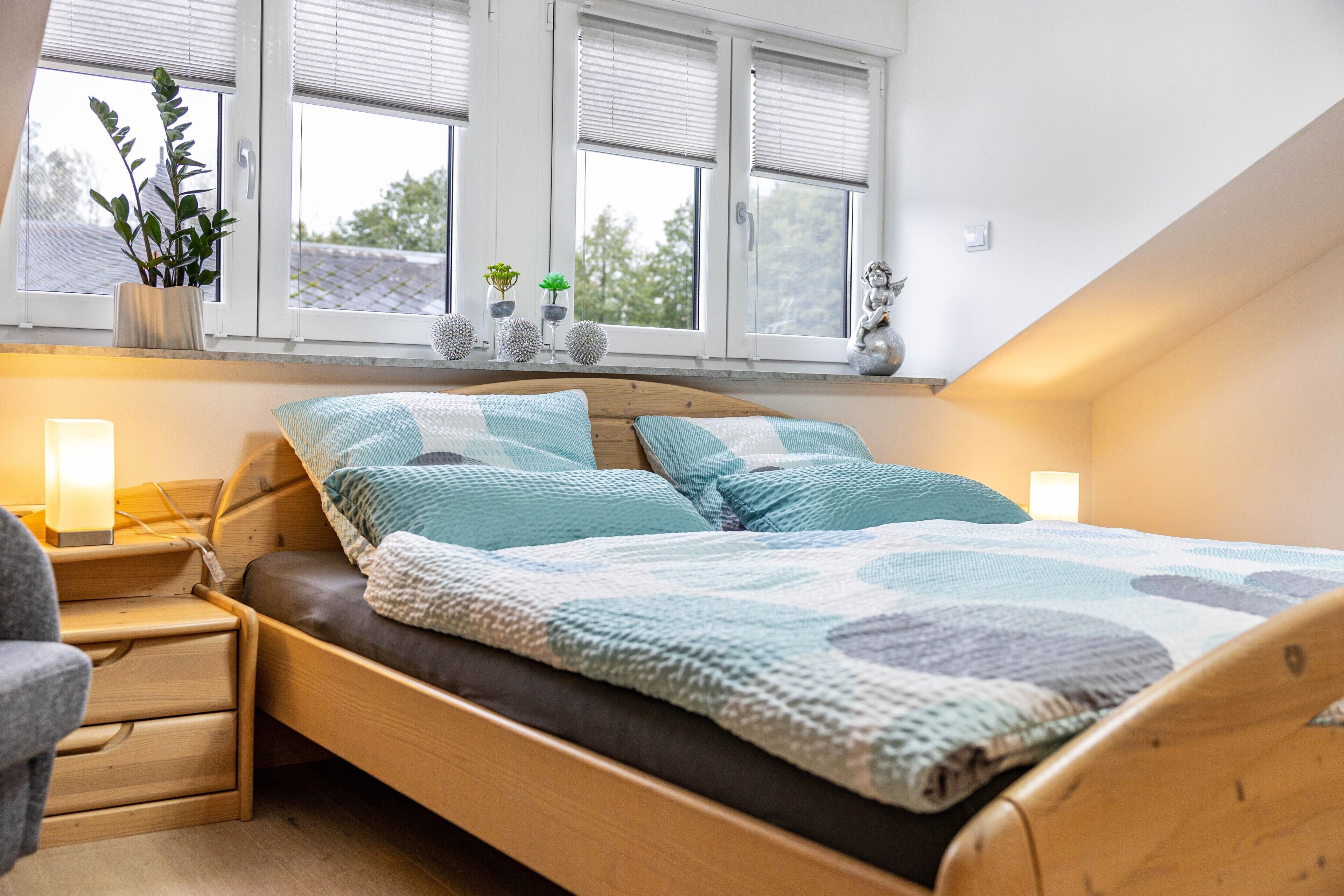 Een slaapkamer met een houten bed, nachtkastje, stoel en een raam met jaloezieën.