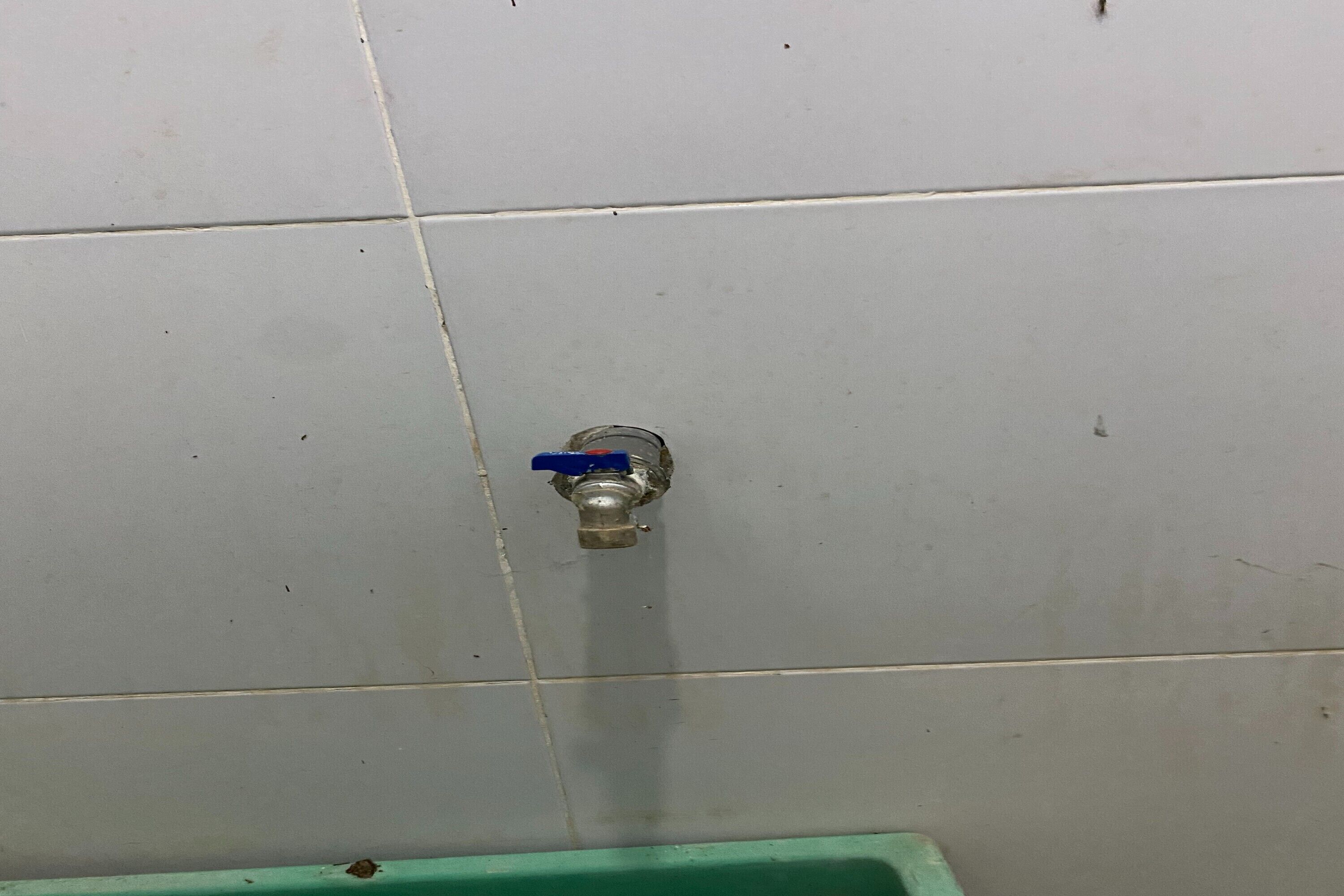 Un baño con un lavamanos verde y un grifo de pared.