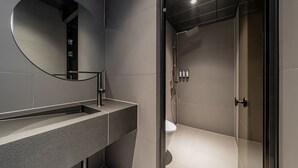 Une salle de bain moderne avec un grand miroir, un lavabo et un espace douche.