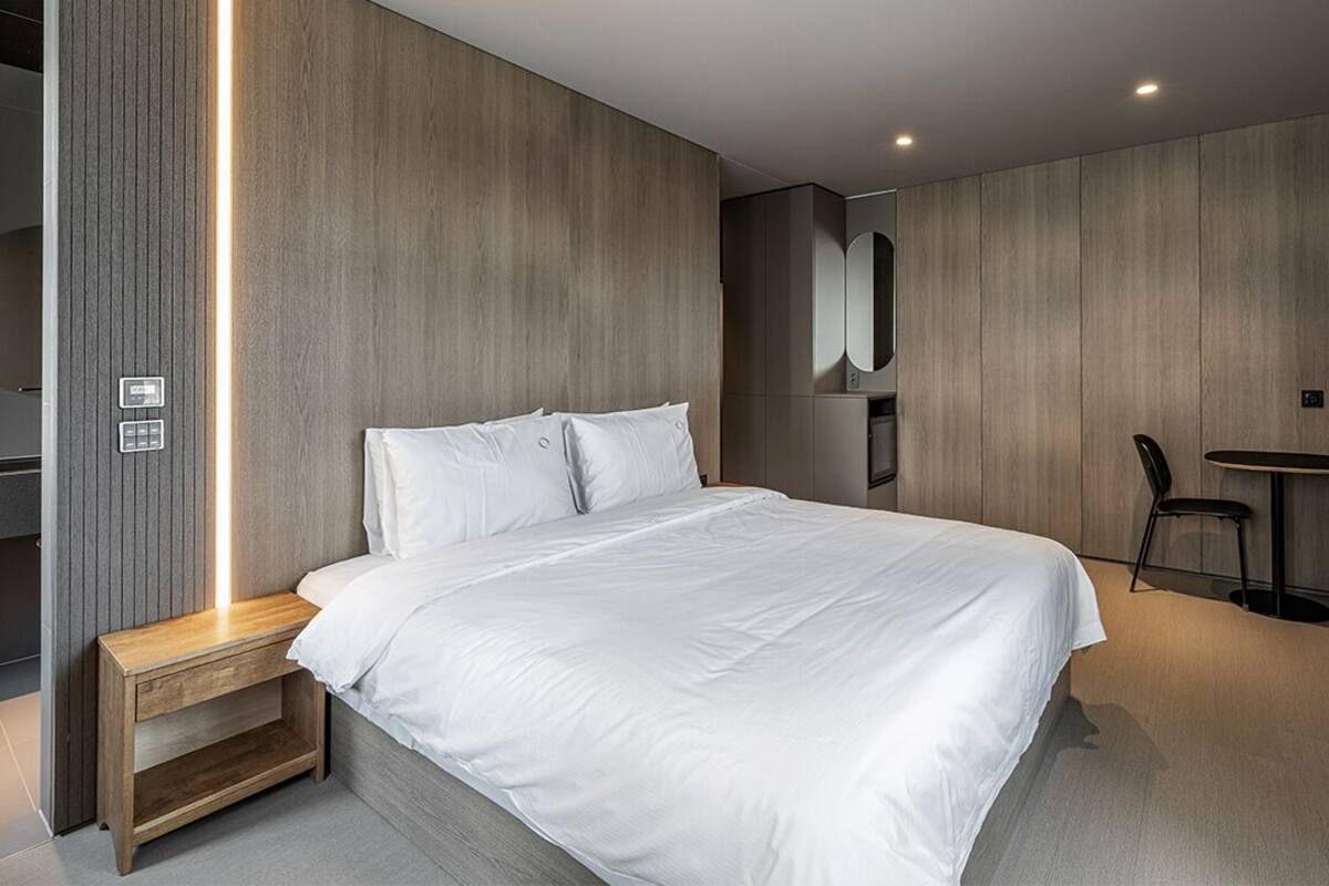 Un dormitorio moderno con una cama grande, una mesita de noche, una silla y un escritorio pequeño.