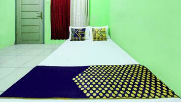 A room with a bed, two pillows, a window with curtains, and a door.