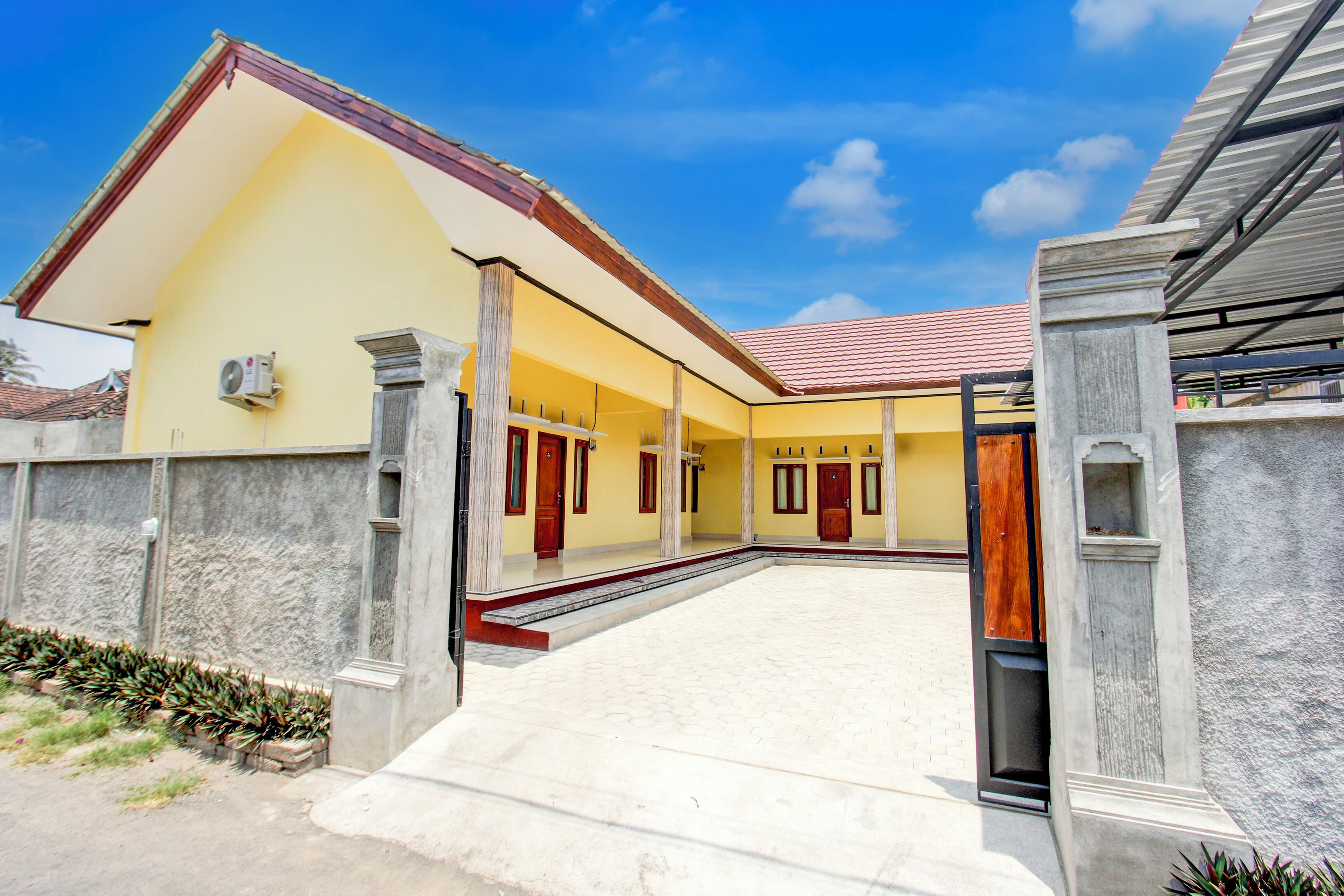 A building with a yellow facade, multiple doors, and a covered entrance area.