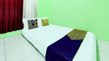 Una cama con ropa blanca, dos almohadas con diseños geométricos y una manta azul.
