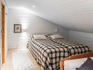 Une chambre avec deux lits, un mur blanc et un tableau encadré.